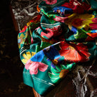 Flat lay of Ines Silk Scarf bunched on marble surface showing full tropical floral pattern and luxurious silk texture