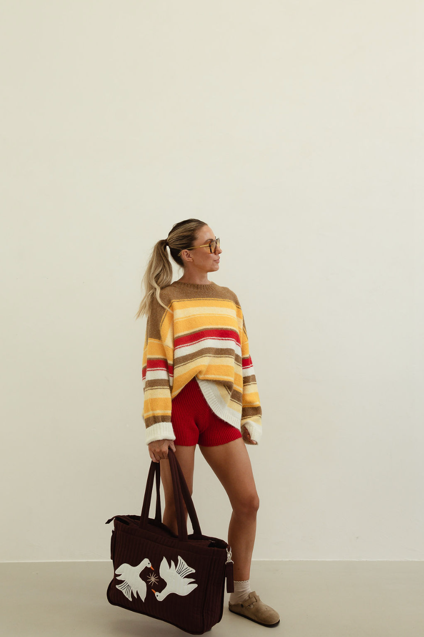 Side profile of model wearing Isabel Knit autumn stripe sweater with long sleeves and crew neckline