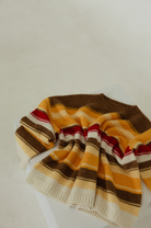 Flat lay of Isabel Knit sweater showing autumn stripe pattern detail with brown yellow red cream stripes