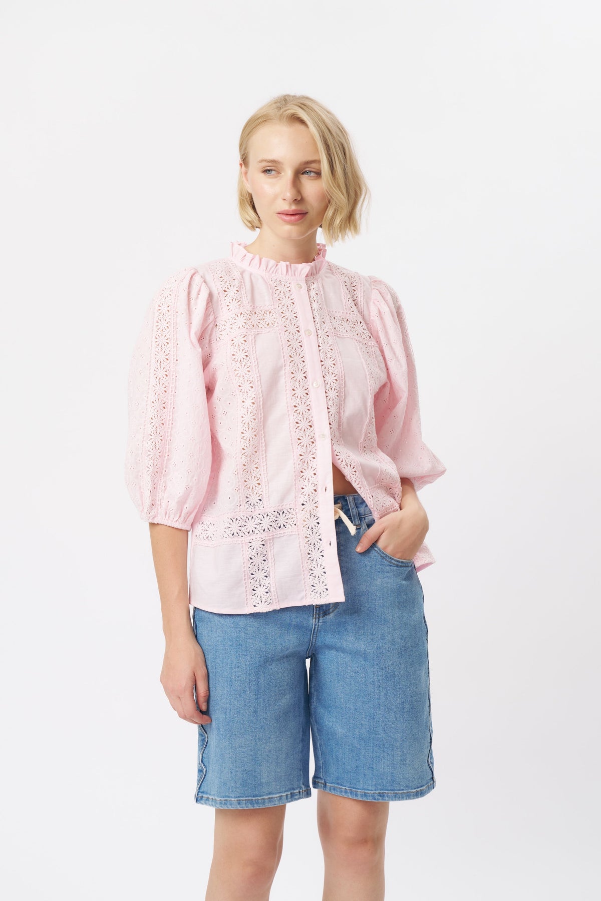 Front full-length view of pink eyelet cotton shirt with puff sleeves, ruffle collar, and button placket