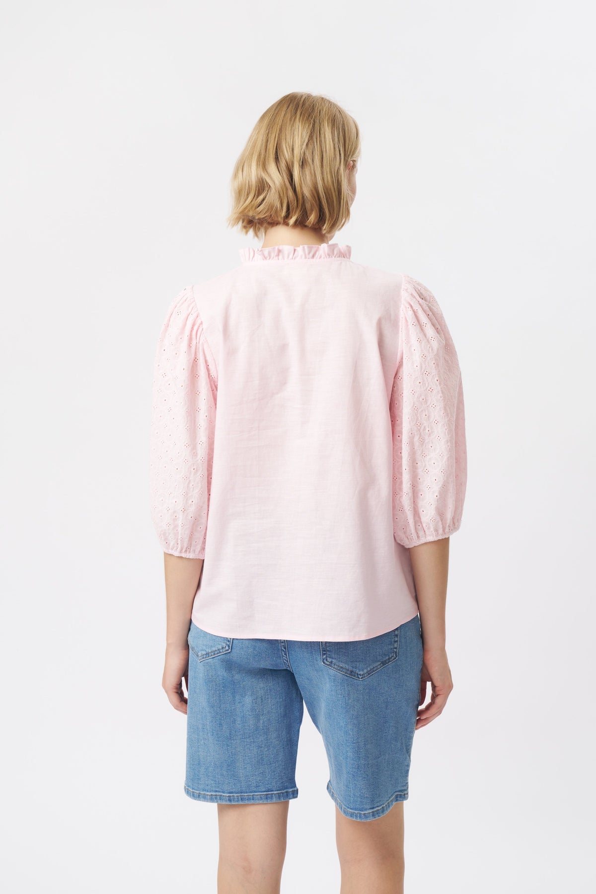Back view of pink puff-sleeve broderie anglaise shirt showing ruffle collar and plain woven back panel