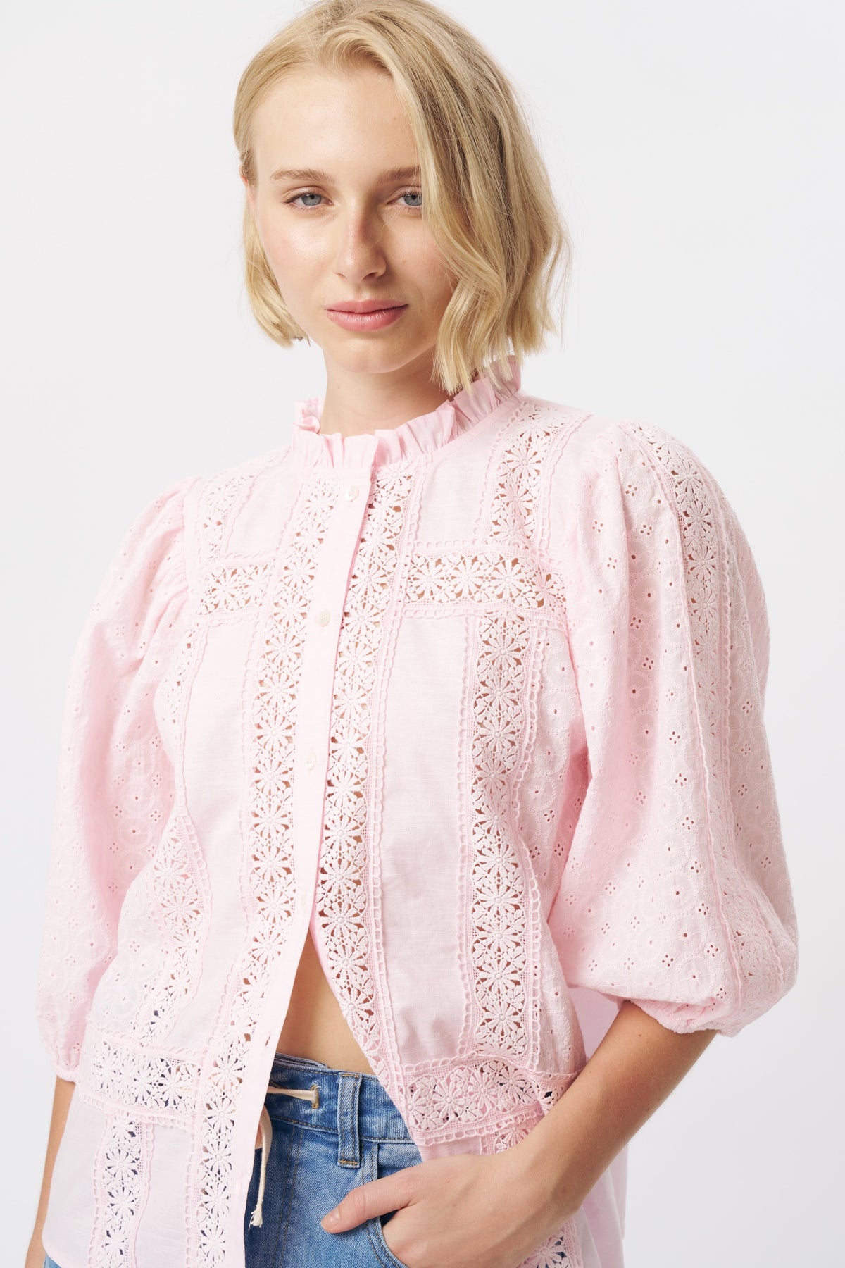 Close-up front detail of pink broderie anglaise shirt highlighting floral eyelet lace panels and puff sleeves