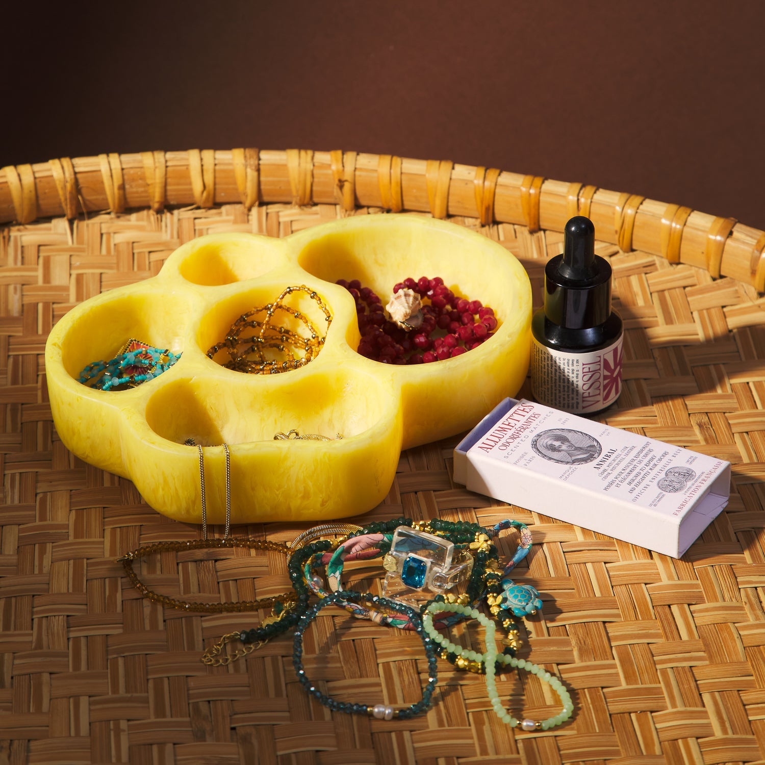 Aspen Gold marbled cloud-shaped dish filled with jewelry and botanicals on a woven rattan tray