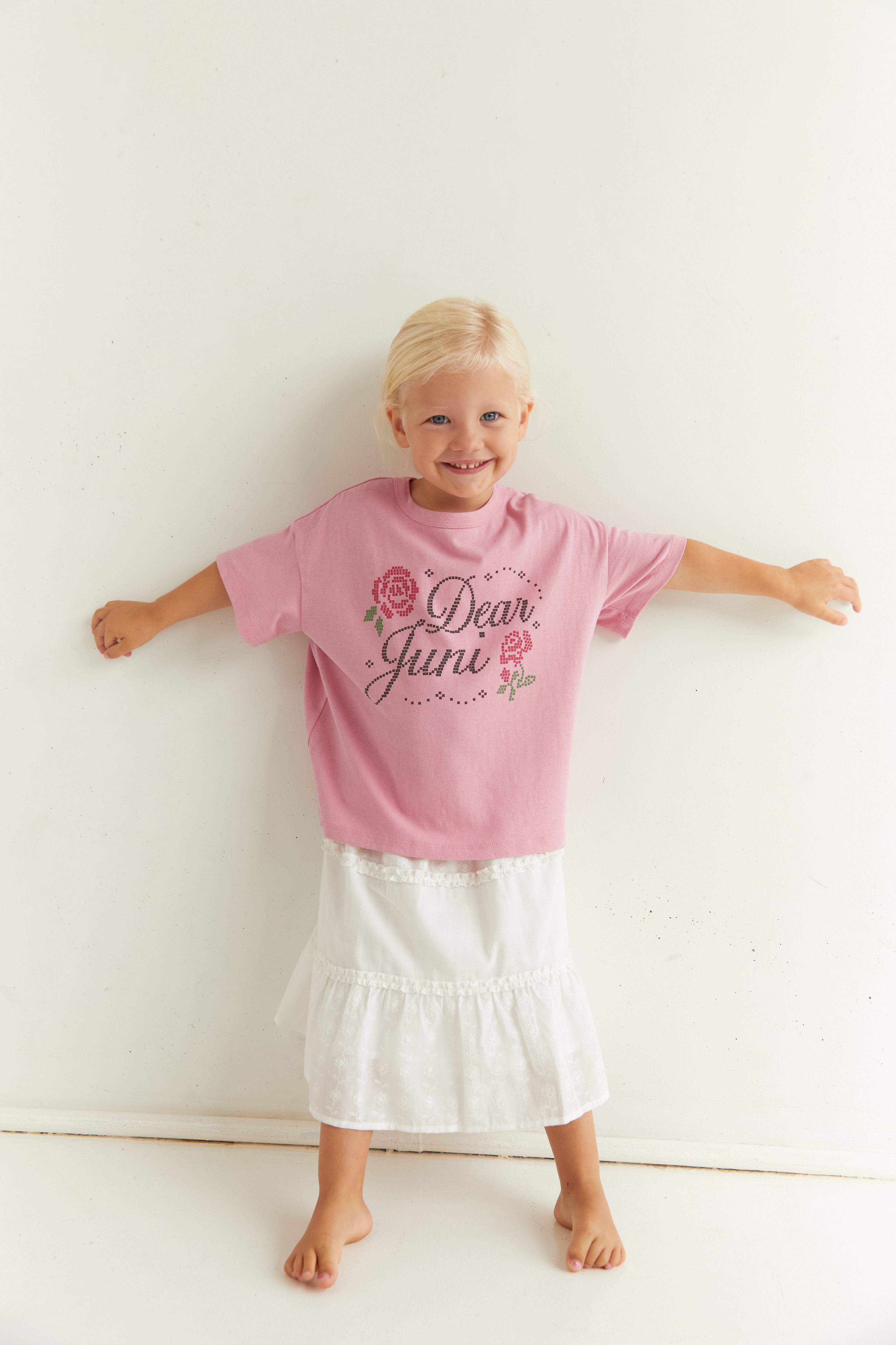 Full front view of child in pink Dear Juni tee with arms outstretched showing fit and design