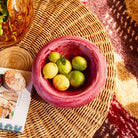 Overhead view of pink marbled resin Jeanne Bowl filled with lemons and limes on wicker coffee table