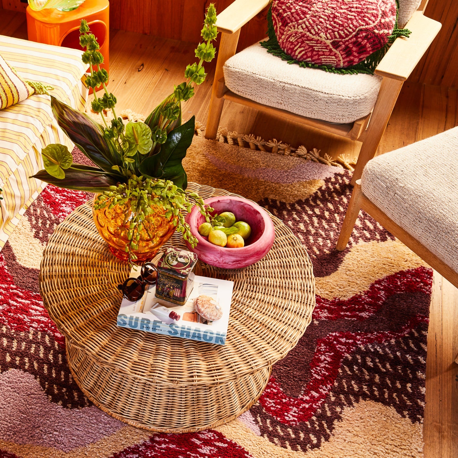 Pink marbled resin Jeanne Bowl with fruit styled on wicker coffee table in colorful boho room setting