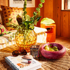 Pink marbled resin Jeanne Bowl filled with citrus fruit styled on rattan coffee table in warm boho interior