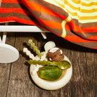 Cream marbled resin Jeanne Bowl with coconut and cucumber styled on wooden floor with striped towels