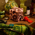Green plaid fringed hand towel draped on a wooden vanity table alongside a pink floral toiletry bag