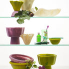 Multiple Joy Pedestal Bowls on glass shelves showing pink cream and green color options