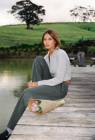 Side angle of stone knit Kaia Zip Cardigan with collar and cropped fit on wooden dock
