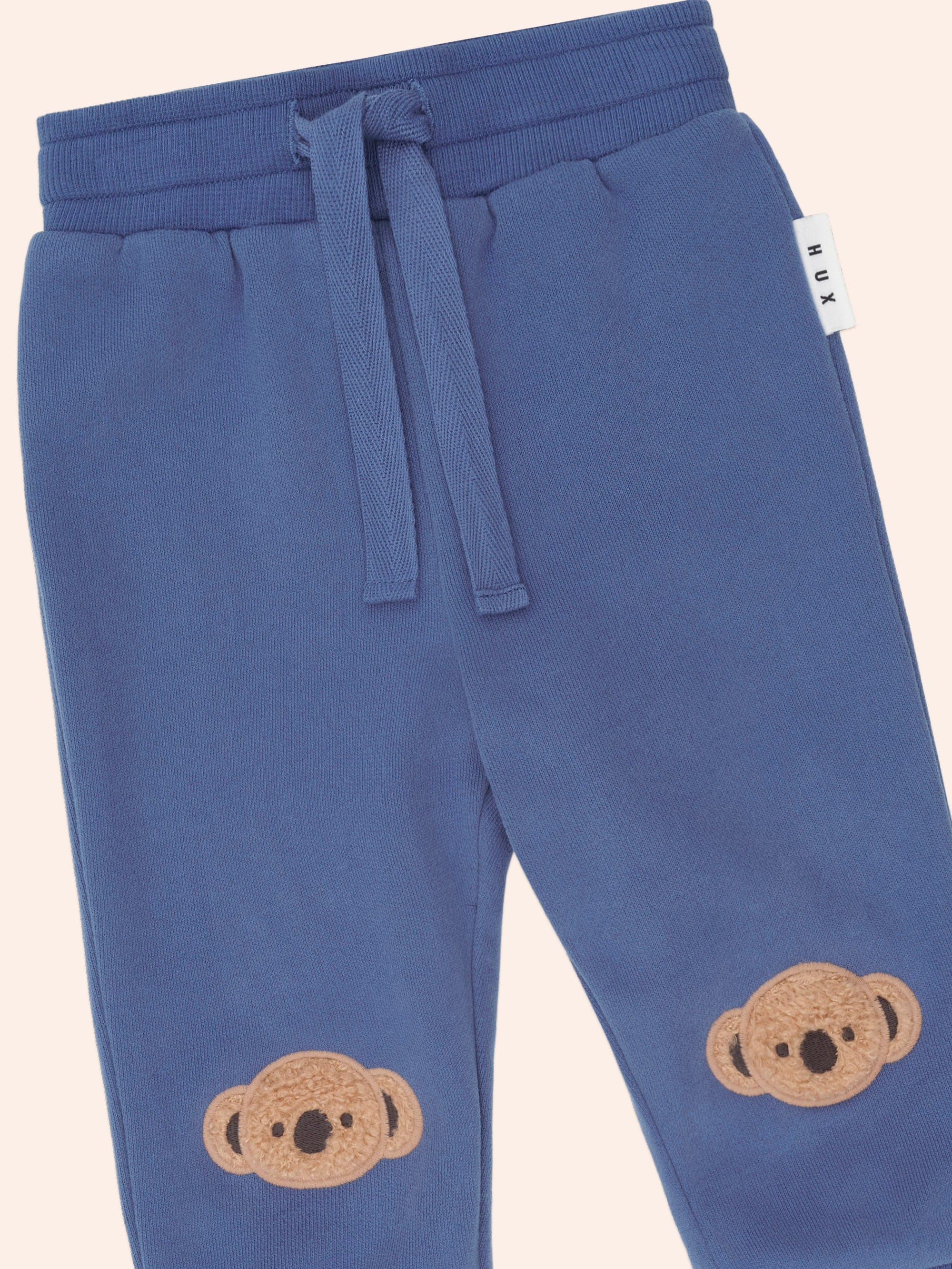 Close-up detail of Huxbaby Kel Koala Trackpant showing drawstring waist and koala face appliques on legs