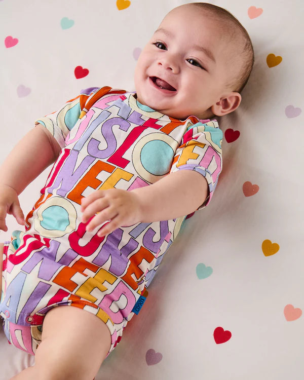 Baby wearing Kip &Co x The Beatles All You Need Is Love Organic Short Sleeve Romper