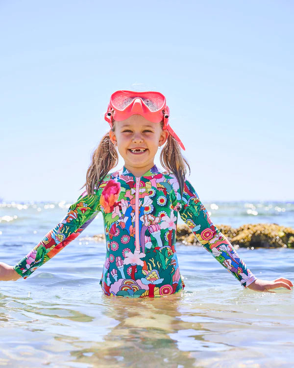 girl at the beach wearing colourful Kip & Co x The Beatles Big Flower Dreamscape Long Sleeve Bathers