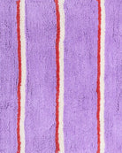 Close-up detail of lavender purple terry cloth fabric with red and cream vertical stripe pattern texture