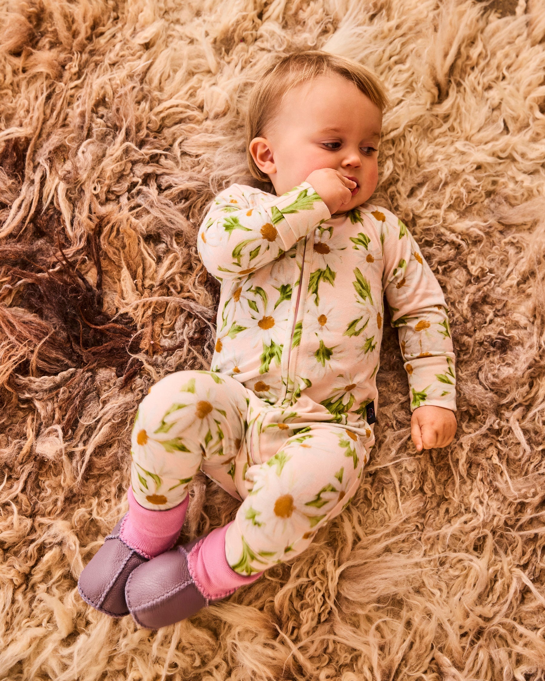 Baby wearing lilac booties with pink knit socks on soft textured blanket surface
