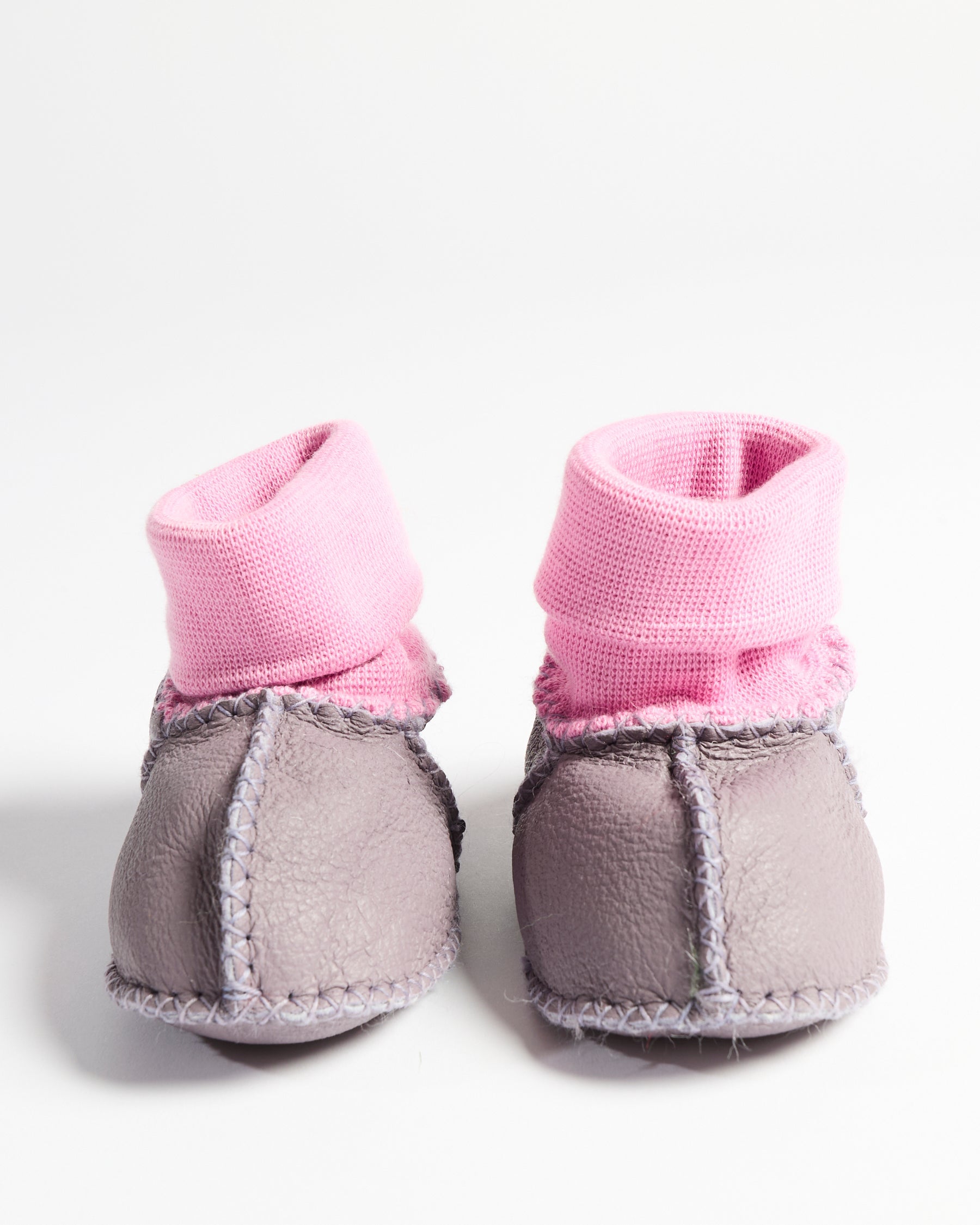 Front view of pair of lilac baby booties showing pink knit cuffs and gray leather construction