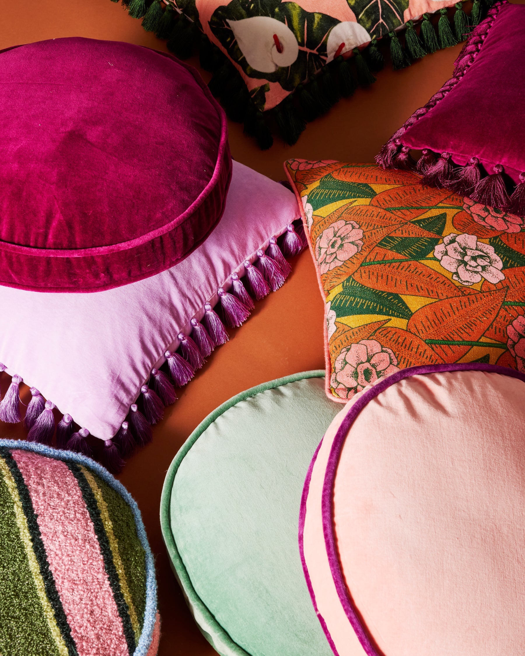 Colorful flat lay of velvet tassel cushions including lilac purple cushion with decorative trim