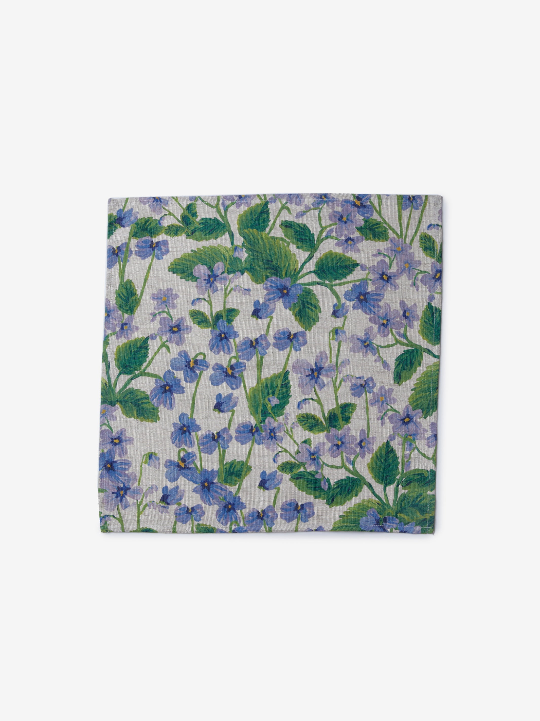 Close-up of Lilas Blue napkins with purple floral pattern and green leaves displayed on dining table
