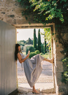 Woman reading a book in a scenic outdoor setting with stone walls and greenery.