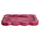 Crimson pink marbled resin tray with scalloped edges, angled side view on white background