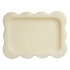 Yellow marbled resin scalloped tray styled on tiled surface holding jewelry glasses and trinkets