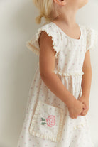 Side detail of Lola Dress showing ruffle sleeves and embroidered rose pocket trim