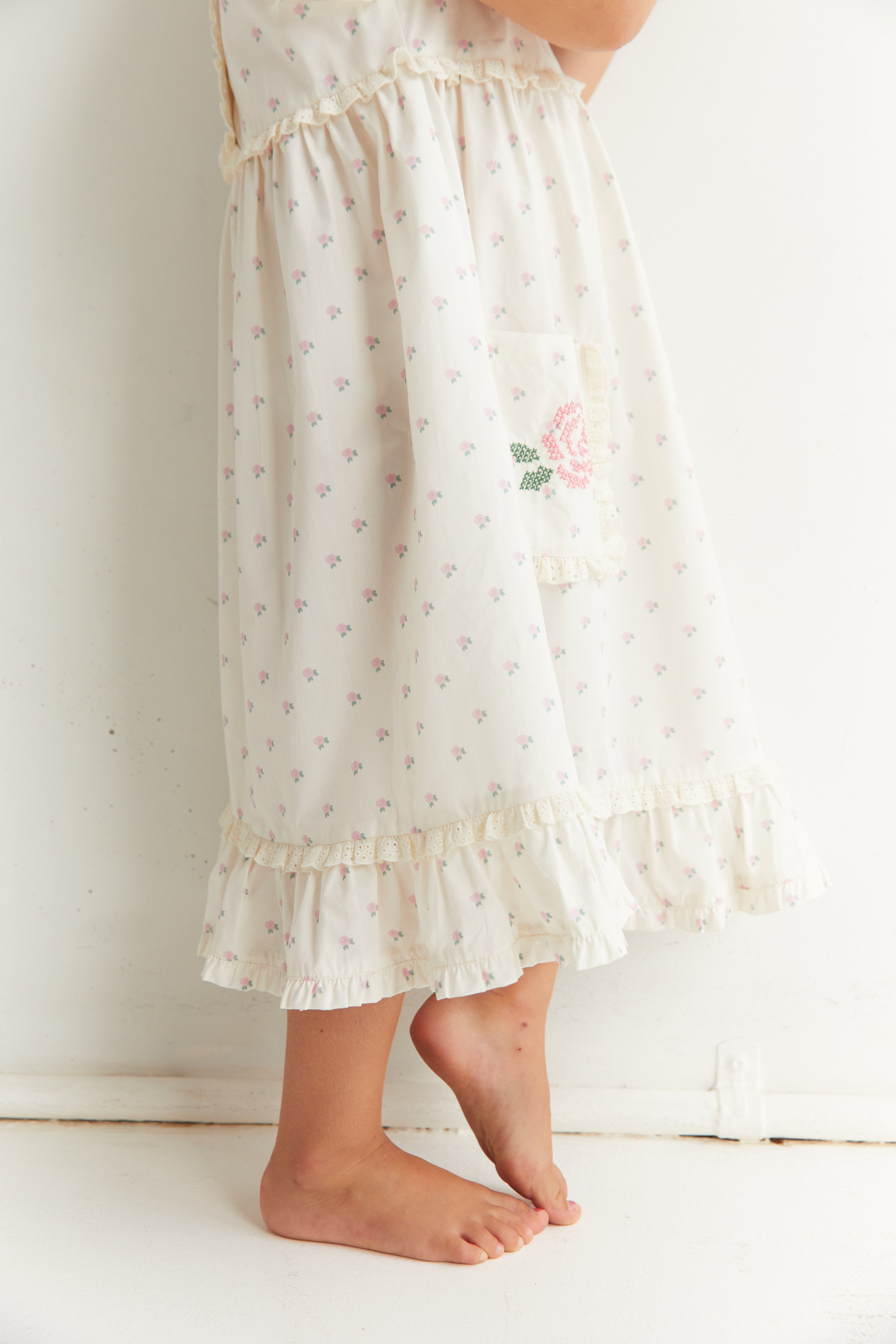 Lower view of Lola Dress showing ruffle hem and embroidered rose pocket detail