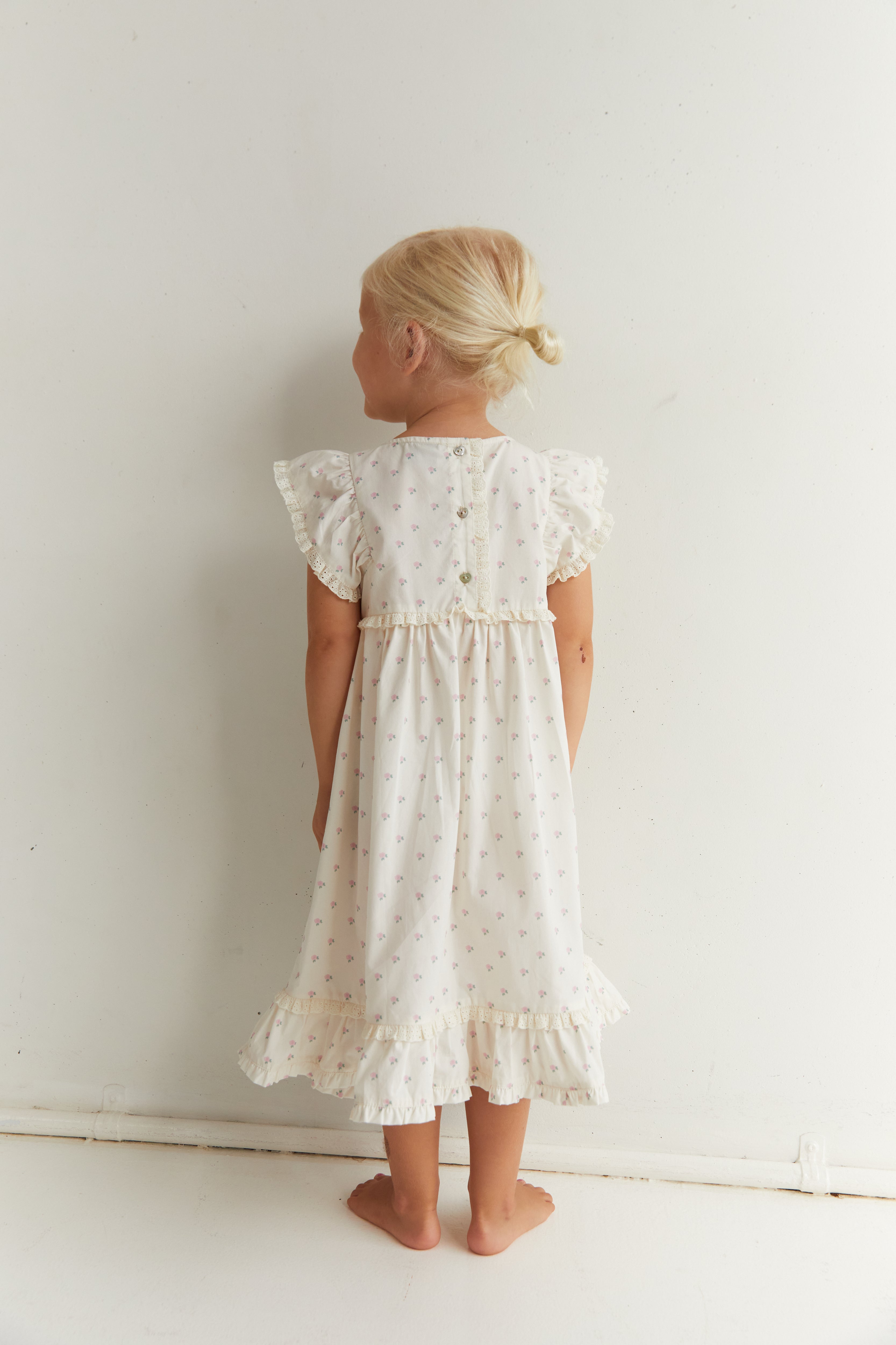 Back view of Lola Dress with roses print showing button closure and ruffle sleeves