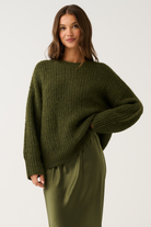 Three-quarter front view of an olive green oversized ribbed knit sweater with relaxed long sleeves and round neckline