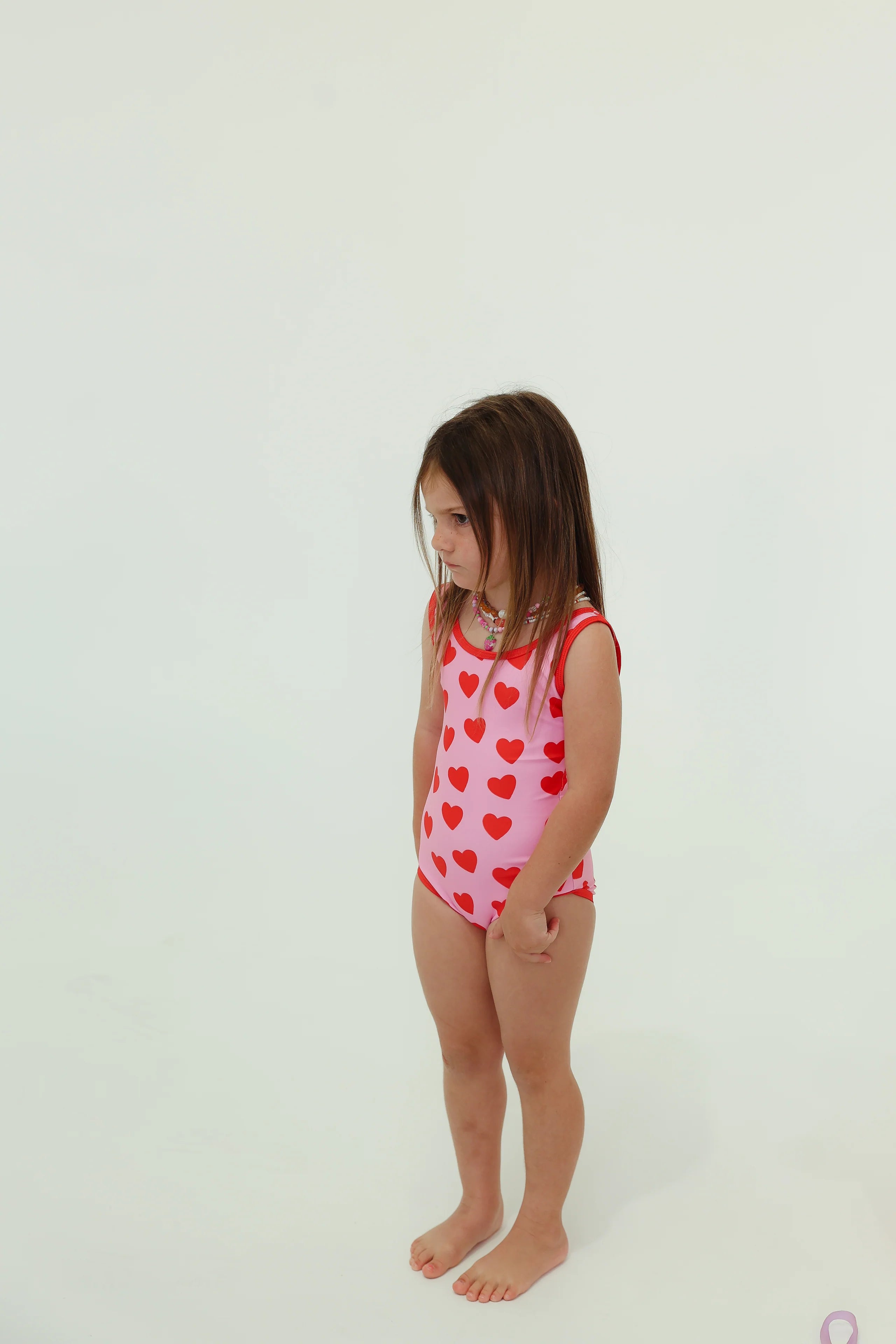girl wearing pink one piece swimsuit with red hearts