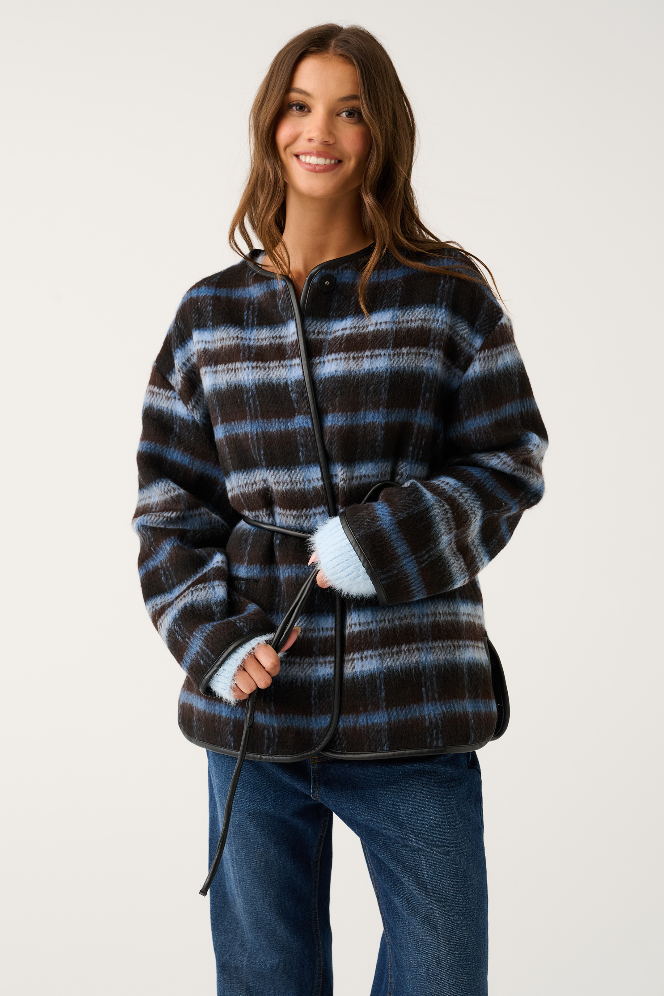 Front view of a blue and brown check oversized jacket with black leather trim, snap collar, and tie belt