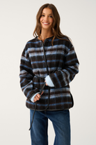 Front view of a blue and brown check oversized jacket with black leather trim, snap collar, and tie belt