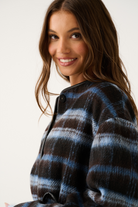 Close-up side view of a blue and brown check jacket showing the black leather trim neckline and snap button
