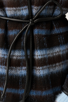 Detail shot of the black leather knot tie belt on a blue and brown check textured jacket
