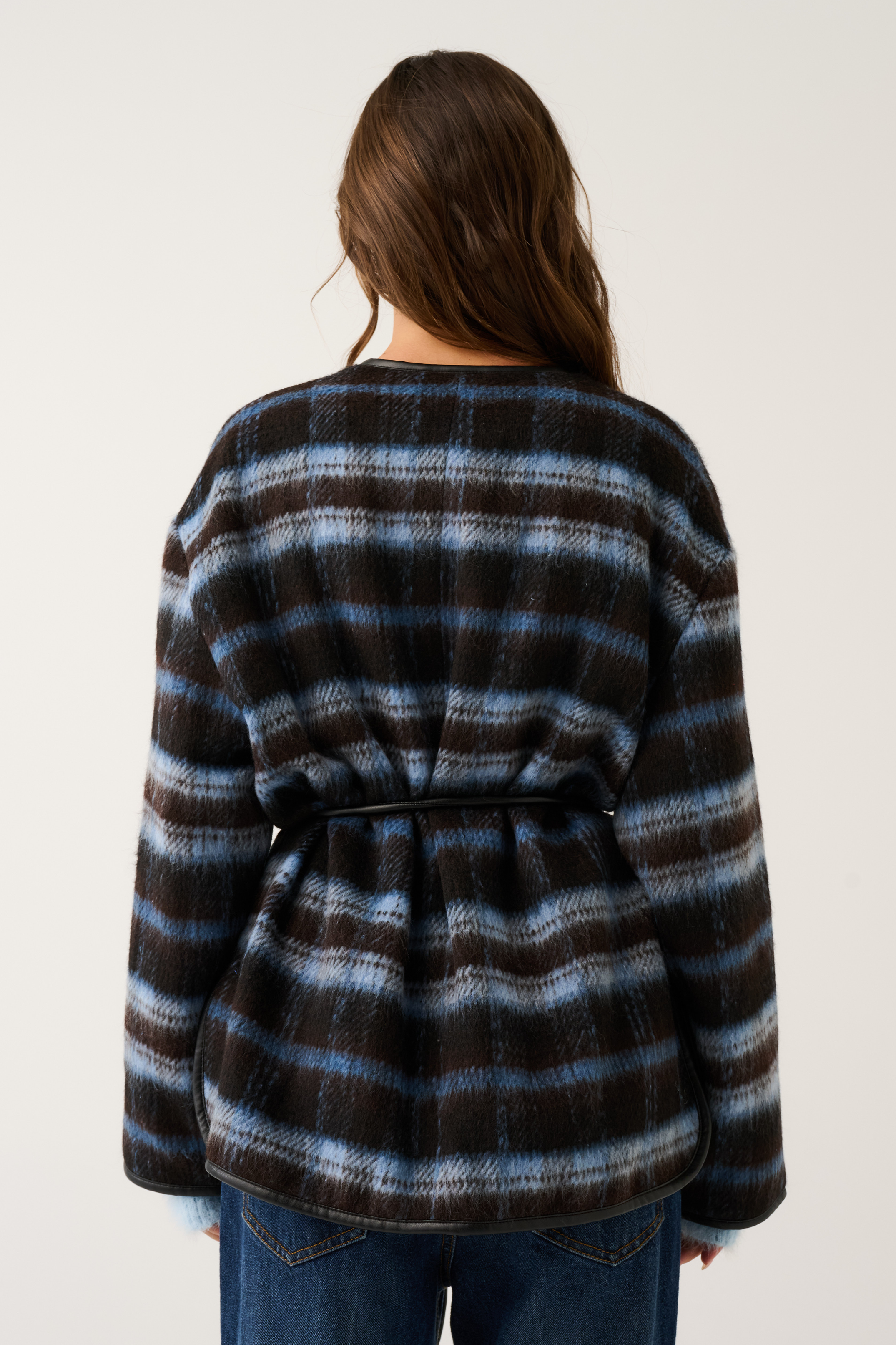 Back view of a blue and brown check oversized jacket with black leather belt tie and fluffy cuffs