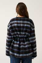 Back view of a blue and brown check oversized jacket with black leather belt tie and fluffy cuffs