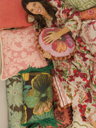 Model wearing Lupin Multi Linen Robe with floral pattern while relaxing in bed with decorative pillows