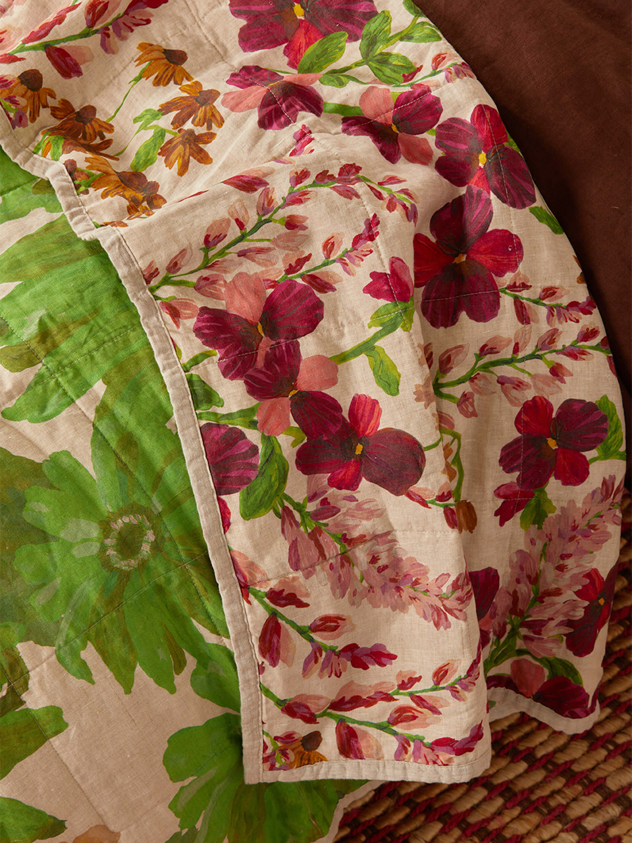 Detail view of Marigold Leaf quilted throw edge showing red floral pattern and stitched binding