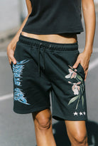 Front view of Sea Street Metallic Boy Track Short in washed black with blue metallic text and floral graphics