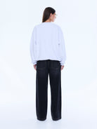 Back view of white oversized sweater showing plain back design and loose fit