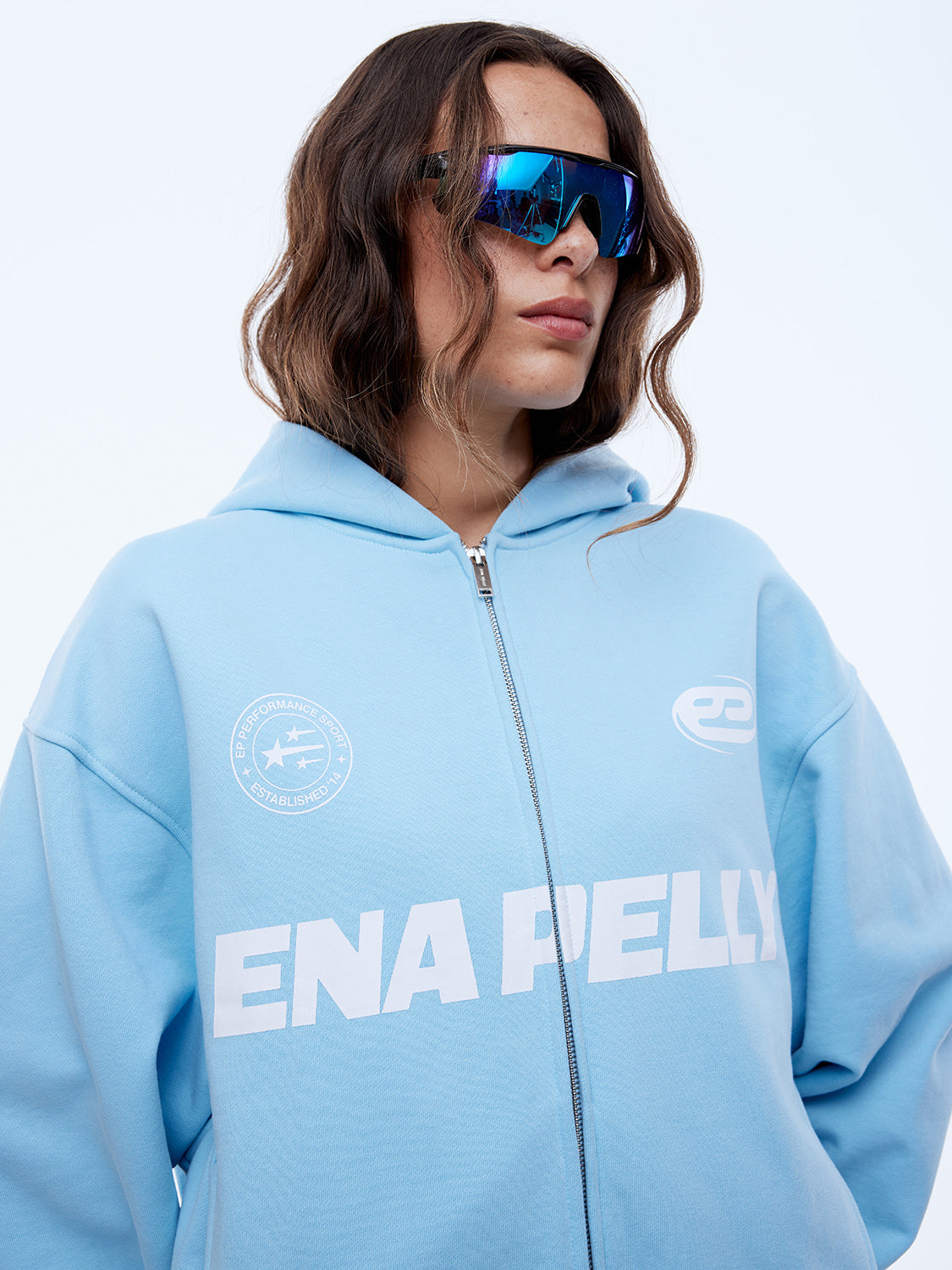 Close-up front view of cloud blue zip-up hoodie showing multi logo design and hood detail
