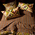 Pair of geometric triangle print linen pillowcases styled on a boho bed with mixed patterned bedding