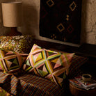Two geometric triangle print linen pillowcases displayed on a cosy bed with warm ambient lighting