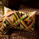 Pair of linen pillowcases with bold multicolour geometric triangle print resting on patterned bedding