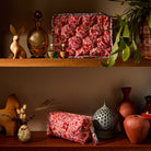 Poppy Magnolia Vanity Bag displayed open and closed on wooden shelves with eclectic decor