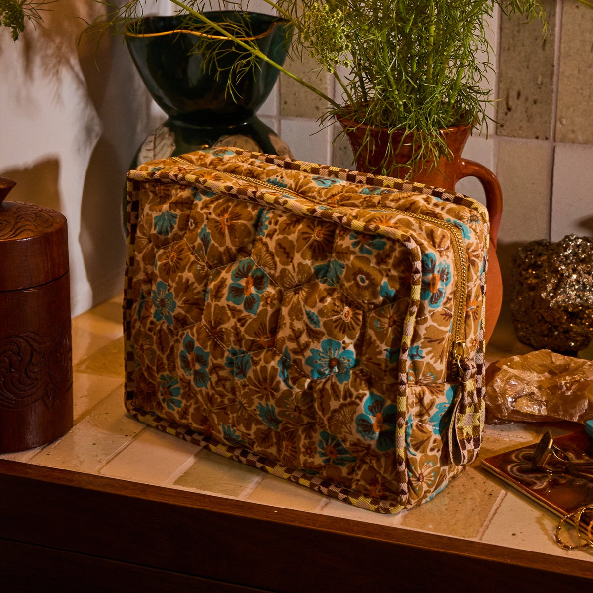 Turquoise Magnolia Vanity Bag styled on a tiled surface beside plants and decorative objects