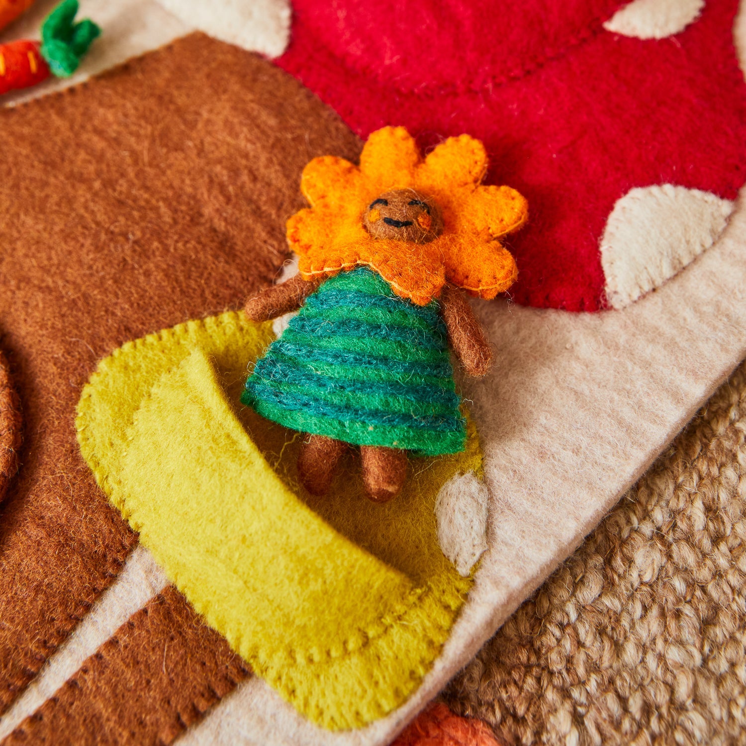 Close-up of orange felt basket with woven brown handle and colorful carrots on mushroom stem