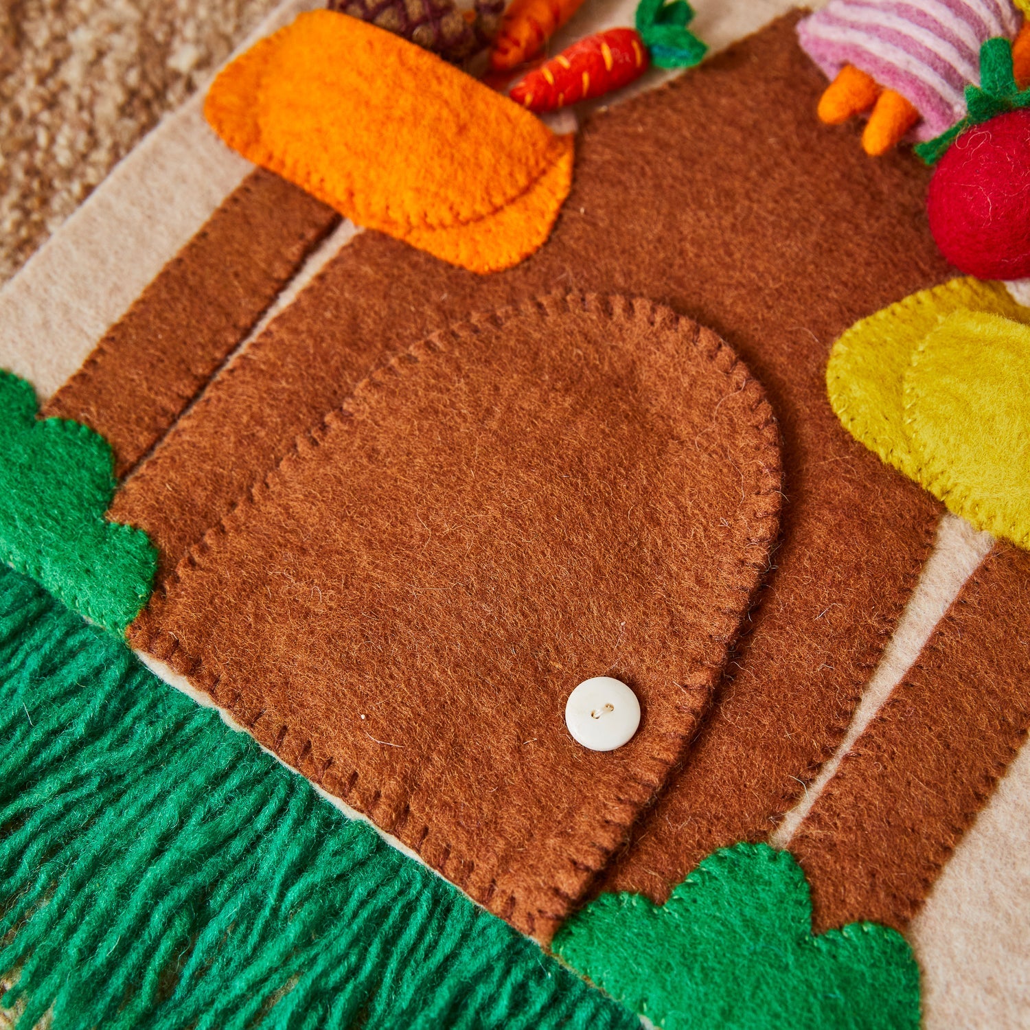 Orange felt flower with brown center attached to green cone-shaped element on brown mushroom stem