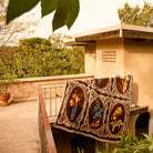 Brown velvet bedcover with six botanical floral medallion panels and cream fringe trim draped over a balcony railing outdoors